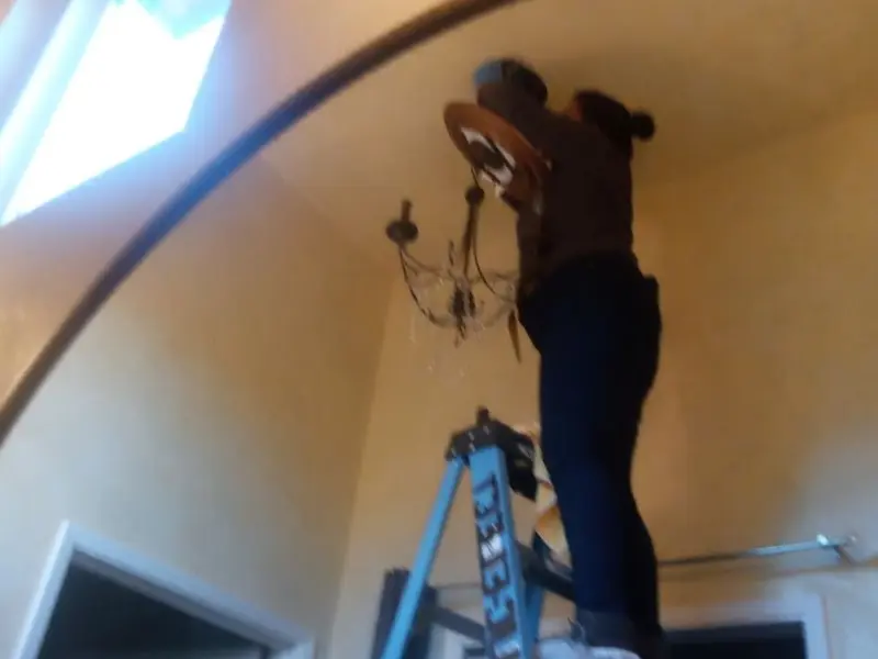 Electrician installing a chandelier in a Norwood residence